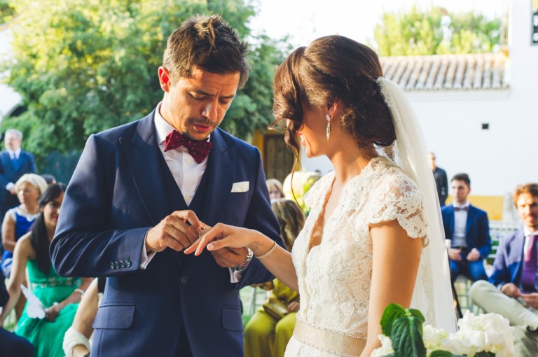 novio metiendo anillo en el dedo de la novia